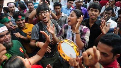 Bangladeshi social activists raise their hands in celebration after hearing the International Crimes Tribunal's guilty verdict on Mohammad Kamaruzzaman.