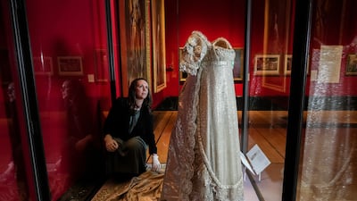 Anna Reynolds, exhibition curator, adjusts the earliest surviving British royal wedding dress, worn by Princess Charlotte of Wales. PA