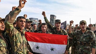 Syrian government soldiers chant slogans with a national flag and portraits of President Bashar al-Assad near the outskirts of the northern city of Manbij in the north of Aleppo province. AFP