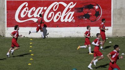 Bolivia players run past a Coca Cola sign on Monday during their training session for a 2018 World Cup qualifying match against Uruguay on Thursday. David Mercado / Reuters