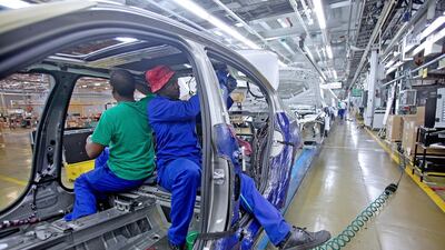 Workers fit electrical cables to the interior of a BMW 3 Series as it passes along the production line in Rosslyn, South Africa. Kevin Sutherland / Bloomberg