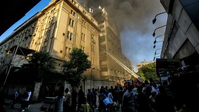 People look on as firefighters douse the flames. AFP