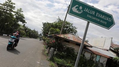 A woman rides a motorbike past a sign pointing at a tsunami evacuation route in Banda Aceh, Indonesia. EPA