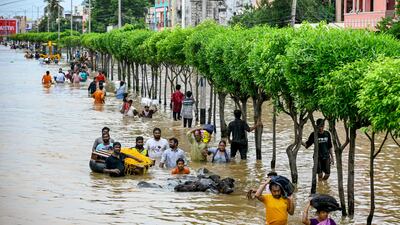 People carry their belongings as they wade through flooded streets after heavy monsoon rains, in Vijayawada, India. AFP
