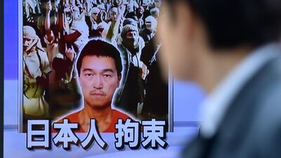 A pedestrian looks at a TV screen in Tokyo on January 26 showing news reports about Japanese journalist Kenji Goto being held by militants. AFP Photo