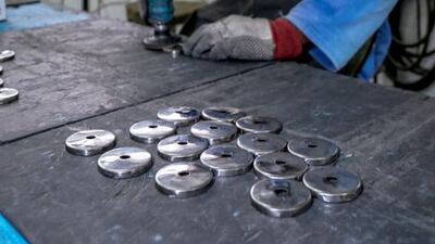 A worker buffs stainless steel washers.