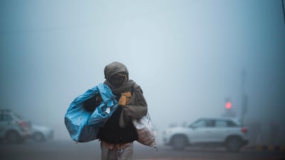 TOPSHOT - A man crosses a street under heavy foggy conditions in New Delhi on December 30, 2019. / AFP / Jewel SAMAD