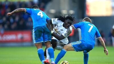 Swansea City's Bafetimbi Gomis, centre, is tackled by Sunderland's Liam Bridcutt, left, and Sebastian Larsson during their English Premier League match at The Liberty Stadium in Swansea, Wales, on February 7, 2015. Nick Potts / AP Photo