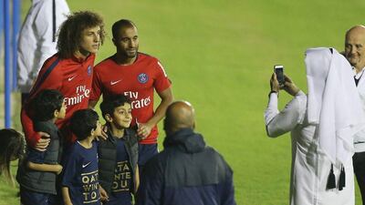 Paris Saint-Germain's (PSG) Brazilian defender David Luiz (L) and Brazilian midfielder Lucas Moura pose for pictures after a training session at the team's training camp in the Qatari capital Doha, on December 29, 2015 on the eve of their friendly football match against Italian league leaders Inter Milan. AFP PHOTO / KARIM JAAFAR