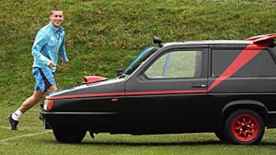 Portsmouth FC's Sean Davies runs past his "A-Team" resprayed Robin Reliant. The car is given to the squad member who has the worst Champions League predictions every year to modify for the amusement of the team.