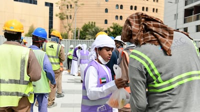 Mubarak Saeed Al Mazrouei, 5, a young Emirati volunteer hands out food to construction workers in Abu Dhabi.