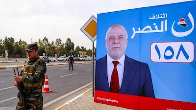 A member of Kurdish security stands near a campaign banner for Iraqi Prime Minister Haider Al Abadi, for the upcoming parliamentary elections in the capital of the northern Iraqi Kurdish autonomous region Irbil on April 26, 2018. / AFP PHOTO / SAFIN HAMED