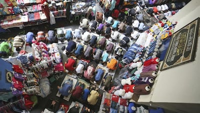 Muslim men perform Friday prayer amid clothing displayed at fashion stalls in Tanah Abang market in Jakarta, Indonesia. Achmad Ibrahim / AP Photo
