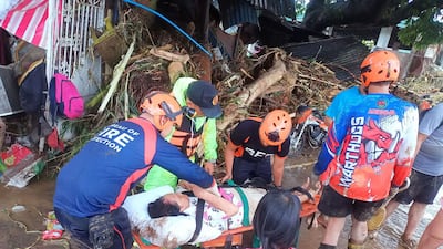 Personnel prepare to evacuate a resident next to a damaged house with debris swept away by flash floods at the height of Typhoon Kalmaegi at a village in La Carlota City, Negros Oriental province, central Philippines. AFP