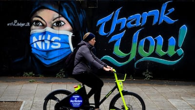A woman cycles past a piece of street art thanking the NHS in London, England. Getty Images
