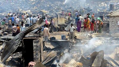 Indian residents gather among damaged homes as firefighters spray water to douse flames after fire broke out in a makeshift settlement in New Delhi. More than 600 homes were destroyed in the blaze. The cause of the fire is not yet known, fire department officials said. Ravendreendran / AFP / April 25, 2014