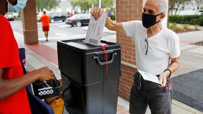 Florida resident Valentine Lugo casts his mail-in ballot at the Winter Garden Library polling station as early voting begins ahead of the election in Orlando. Reuters
