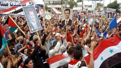 A handout picture made from the official Syrian Arab News Agency shows Syrian citizens holding the national flags and photos depicting President Bashar Assad as they gather to celebrate his victory in presidential elections, in Latakia province, Syria on 5 May 2014. EPA/Sana handout