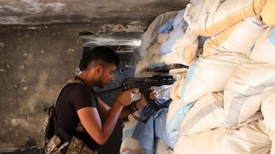 Moawiya Sayasina aims a Kalashnikov assault rifle through sandbags at a fortified position near the frontline in a rebel-held neighbourhood in the southern Syrian city of Daraa. Mohamad Abazeed / AFP