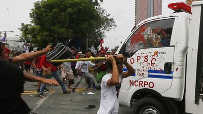 A man hits a Philippine National Police van with a stick after it rammed anti-US protesters outside the American embassy in Manila.