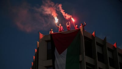 Protesters who hung a huge Palestinian flag from a building facing the Israeli embassy light flares during a protest over the interception of the Gaza aid flotilla, in Athens. Reuters