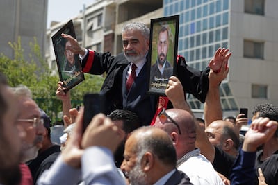 Syrians carry pictures of relatives killed during the country's civil war, as they celebrate the sentencing outside the Palace of Justice in Damascus. AFP