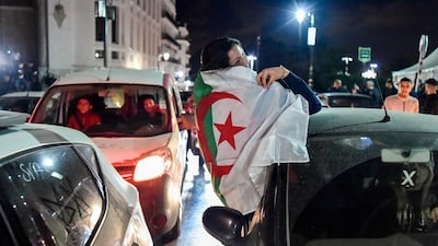 An Algerian woman draped in a national flag sits out from the window of a car during demonstrations in the centre of the capital Algiers on March 11, 2019, after President Abdelaziz Bouteflika announced his withdrawal from a bid to win another term in office and postponed an April 18 election, following weeks of protests against his candidacy. Bouteflika, in a message carried by national news agency APS, said the presidential poll would follow a national conference on political and constitutional reform to be drawn up by the end of 2019. / AFP / RYAD KRAMDI