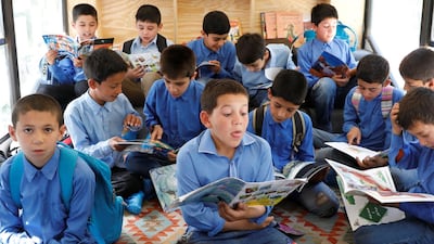 Boys read books inside a mobile library bus.