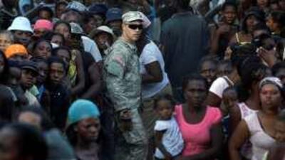 A soldier of the US 82nd Airborne Division maintains order as a crowd of people line up for water distribution in Port-au-Prince.