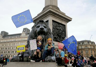 Demonstrators sit next to one of the lions in Trafalgar Square during the Peoples Vote anti-Brexit march in London on March 23, 2019. AP Photo