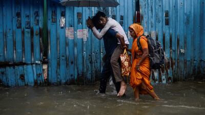 A man carries a family member on his back through a flooded street. Reuters