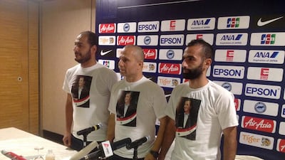 A Syrian football association official, left, head coach Fajr Ibrahim, and midfielder Osama Omari attend a news conference at a Singapore hotel on November 16, 2015, wearing T-shirts of a smiling Bashir Al Assad, the country's embattled president. The coach went on to say he wanted to keep politics out of sport. Patrick Johnston / Reuters