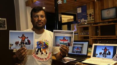 Indian climber Satyarup Sidhantha holds a photograph that shows him on Mount Everest, along with what he says is an altered version of the same used by a couple to make it appear they were on the summit. Bikas Das / AP