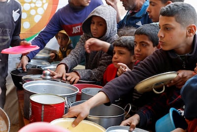 Palestinian children wait to receive food cooked by a charity kitchen in Khan Younis, southern Gaza. Reuters