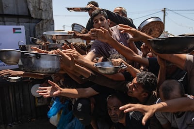 Displaced Palestinians gather to receive hot meals from a charity kitchen in Khan Younis, southern Gaza. EPA