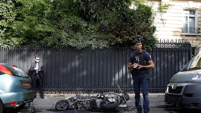 A police officer stands next to a burnt scooter outside the office of Jordan's military attaché in Paris on Wednesday, October 4, 2017. Thibault Camus / The Associated Press