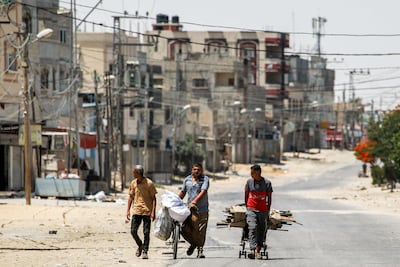 A man pulls a cart loaded with salvaged wood alongside another pushing a bicycle loaded with bags along a street in the eastern part of Rafah in the southern Gaza Strip. AFP