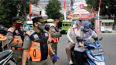 Traffic officers talk to motorists during a mask wearing and public health protocols campaign at a check point in Jakarta, Indonesia. EPA