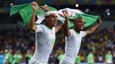 Sofiane Feghouli, left, and Yacine Brahimi celebrate with an Algerian flag after their 1-1 draw with Russia on Thursday night at the 2014 World Cupin Curitiba, Brazil. Matthias Hangst / Getty Images