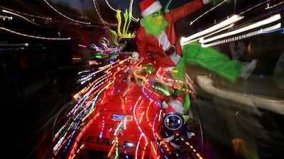 A reveller dressed as the Grinch poses on a car decorated with Christmas lights in Cape Town, South Africa. Reuters