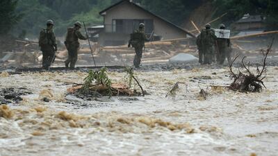 Defense forces soldiers walk beside a river during a search operation for missing poeple in a flooded area in Asakura on July 9, 2017. The death toll from heavy rains and flooding in southern Japan has risen to 15, a government official, as rescuers continued work to evacuate isolated survivors. / AFP PHOTO / JIJI PRESS / STR / Japan OUT