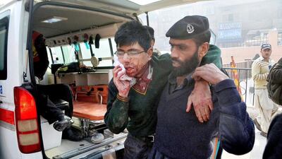 A hospital security guard helps a student injured in the shootout at a school under attack by Taliban gunmen in Peshawar, Pakistan on Tuesday, December 16. Taliban gunmen stormed a military school in the northwestern Pakistani city, killing and wounding dozens, officials said, in the latest militant violence to hit the already troubled region. Mohammad Sajjad / AP