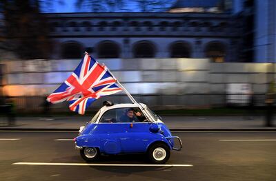 A man waves Union flags from a BMW Isetta as he drives past Brexit supporters gathering in central London on January 31, 2020, the day that the UK formally left the EU. AFP