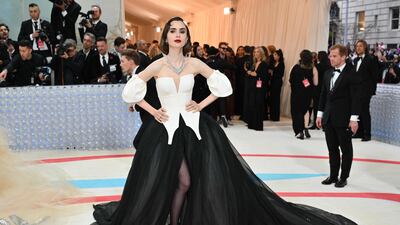 Lily Collins wears a black cape emblazoned with the word 'Karl'. AFP