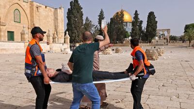 Palestinian medics carry a wounded protester amid clashes with Israeli security forces at Jerusalem's Al Aqsa Mosque compound. AFP