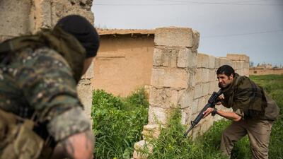 A 26-year old ex-military member from the US, nick-named by Kurdish fighters as Hewal Amed, right, take position during clashes with Islamic State group fighters in the outskirts of the north-western Syrian town of Tal Tamr, north of Hasakeh, near the border with Turkey as he fights alongside People Protection Unit (YPG) fighters under the commanders, Sider and Gerzan.