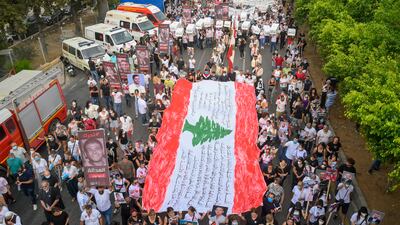People hold the Lebanese flag during a march to the Beirut port. EPA