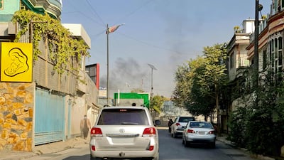 Vehicles drive along a road against the backdrop of smoke rising. AFP