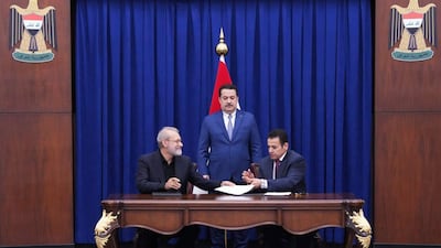 Iraqi Prime Minister Mohammed Shia Al Sudani, centre, oversees the signing of the deal by National Security Adviser Qasim Al Araji, right,and Iranian security chief Ali Larijani. AP