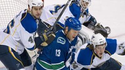 Vancouver's Mats Sundin is challenged by St Louis' Roman Polak, left, TJ Oshie, right, and goaltender Manny Legace.